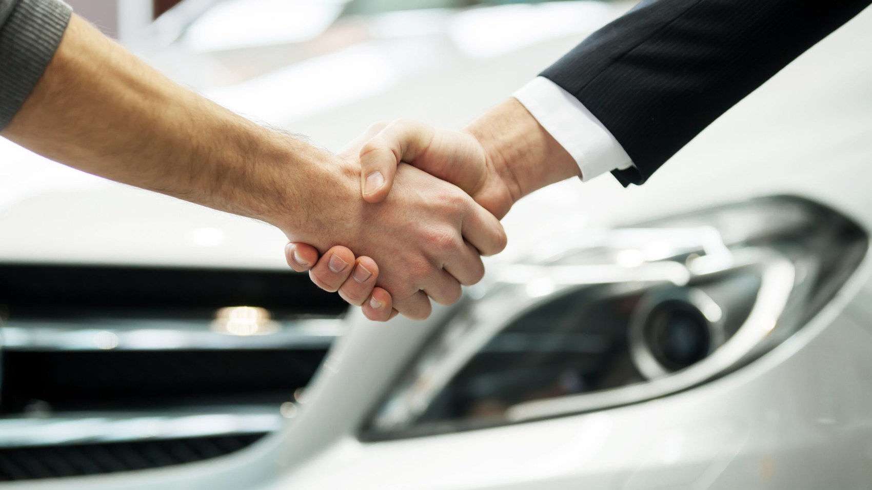Good deal. Close-up shoot of the hands shaking in front of the car
